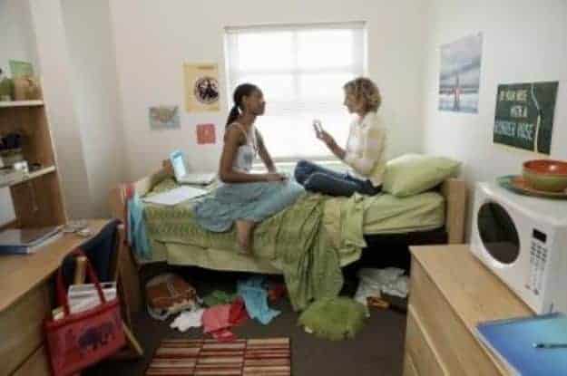 Two girls sitting on a dorm bed talking